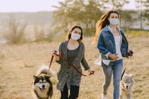 women wearing face masks while running with their dogs
