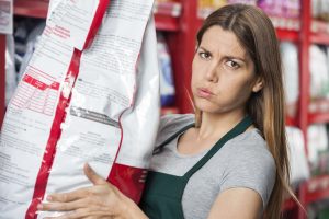 Portrait of mid adult saleswoman carrying heavy food package in pet store